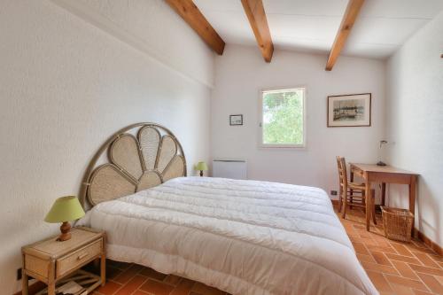 een slaapkamer met een groot wit bed en een tafel bij Echappee insulaire tout pres de la plage in Sainte-Marie-de-Ré