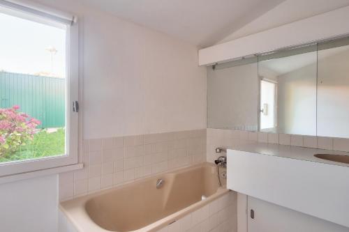 een badkamer met een bad, een wastafel en een raam bij Echappee insulaire tout pres de la plage in Sainte-Marie-de-Ré