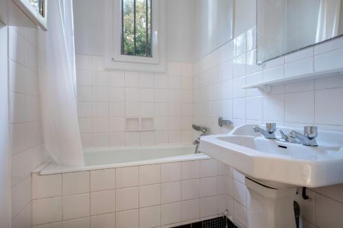 une salle de bain blanche avec un lavabo et une baignoire dans l'établissement Maison à 350m de la plage pour 6 à St Brevin, à Saint-Brévin-les-Pins