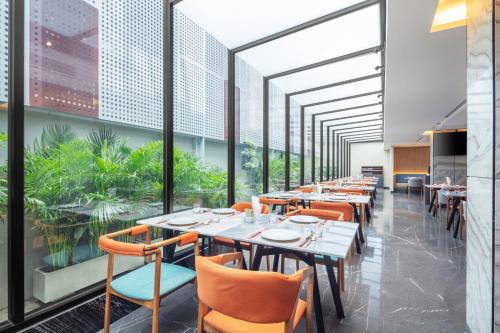 a dining room with tables and chairs and large windows at Best Western Click Sathorn 11 Bangkok in Bangkok