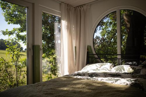 una camera da letto con un letto e una grande finestra di Eulennest - Tiny House im Habichtswald a Schauenburg