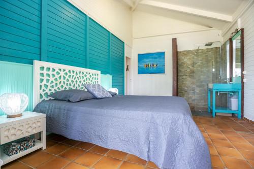 1 dormitorio con cama y pared azul en Villa LALALAND, en Le Gosier