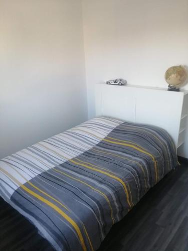 Ce lit se trouve dans un dortoir blanc doté d'une couverture rayée. dans l'établissement Maison Lydie et Manu, à Tournon-sur-Rhône