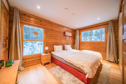 a bedroom with a bed in a room with wooden walls at Levillas Kätkänpolku Villas in Levi
