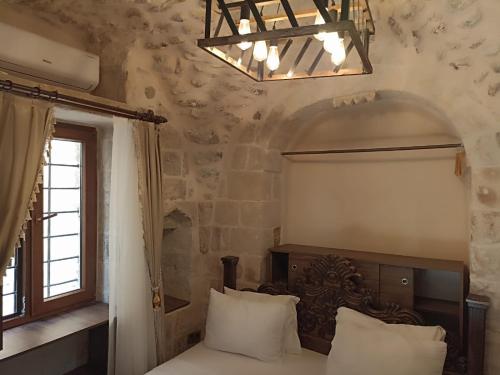 a bedroom with a bed and a window and a chandelier at CARRA KONAĞI in Mardin
