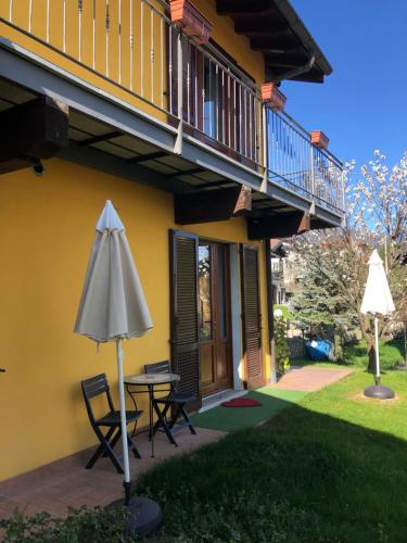 eine Terrasse mit einem Tisch und einem Sonnenschirm neben einem Haus in der Unterkunft In campagna in Besozzo