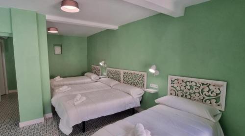 two beds in a room with green walls at La Morada de Moret in Cáceres
