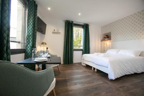 a bedroom with a large bed and a table and a desk at Le Maleville - Balnéo & Ascenseur in Périgueux