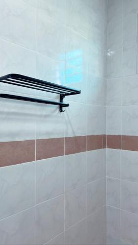 une douche avec une étagère en métal sur un mur dans l'établissement Easy Homestay, à Mukah