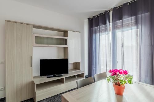 a living room with a table with a television and pink flowers at Zagar House-Venice Airport Close-by Apt W Parking in Campalto
