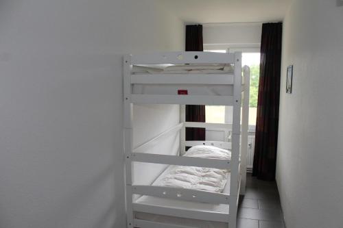 ein weißes Etagenbett in einem Zimmer in der Unterkunft Großzügige Ferienwohnung E328 an der Ostsee in Brasilien