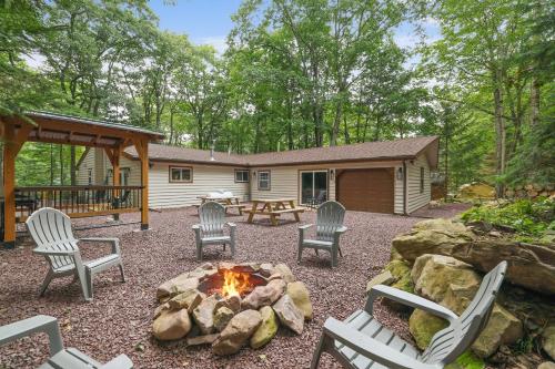 a backyard with chairs and a fire pit and a cabin at Whiskey Pines Retreat! Single Level Home, Outdoor Firepit, AC, BBQ! Sleeps 9 in Lake Harmony! in Lake Harmony