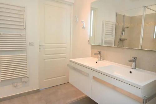 une salle de bain blanche avec un lavabo et un miroir dans l'établissement Les Lucioles - Vue mer, AC, Wi-Fi, 4 pers, à Villefranche-sur-Mer