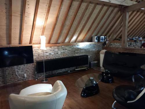 a living room with a fireplace and a white chair at Ruim appartement voor 14 personen in Eijsden