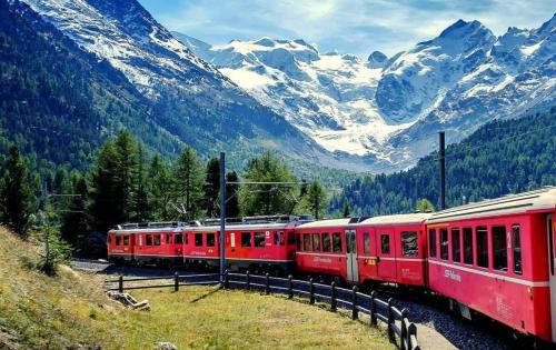 a red train is on the tracks in the mountains at residenza " Il Gufetto" in Lombro