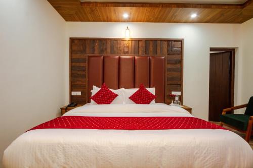 a bedroom with a large bed with red pillows at Tripli Hotels Drilbu Manali in Manāli