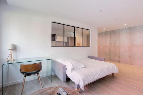 une chambre avec un lit, une chaise et un miroir dans l'établissement Plume - Joli appt refait à neuf, à Strasbourg