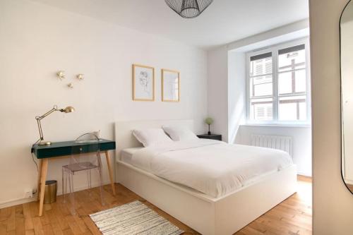 une chambre blanche avec un lit et un bureau dans l'établissement Le Faisan - Bel appt à 200m de la Cathédrale, à Strasbourg
