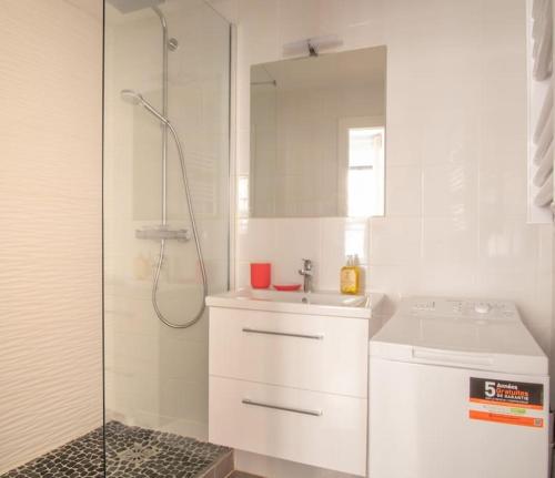 une salle de bain blanche avec une douche et un lavabo dans l'établissement Le Faisan - Bel appt à 200m de la Cathédrale, à Strasbourg