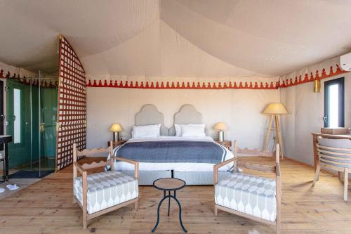a bedroom with a bed and two chairs at Merzouga luxury desert camps in Merzouga