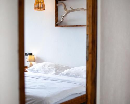 um quarto com uma cama com lençóis brancos e um espelho em Dhiffushi Inn em Dhiffushi