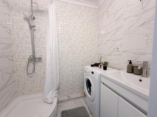 a white bathroom with a shower and a washing machine at Renthouse Apartments City Gates #5 in Chişinău