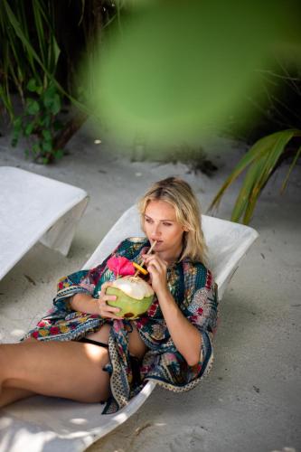 a woman sitting on a pillow eating a fruit at Dhiffushi Inn in Dhiffushi