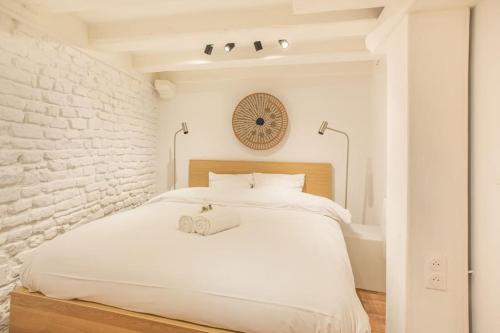 - une chambre blanche avec un lit et un mur en briques dans l'établissement La Halte Strasbourgeoise - Superbe appt près de la Petite France, à Strasbourg