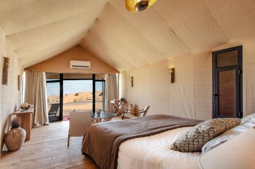 una camera da letto con un grande letto e vista sul deserto di Merzouga luxury desert camps a Merzouga