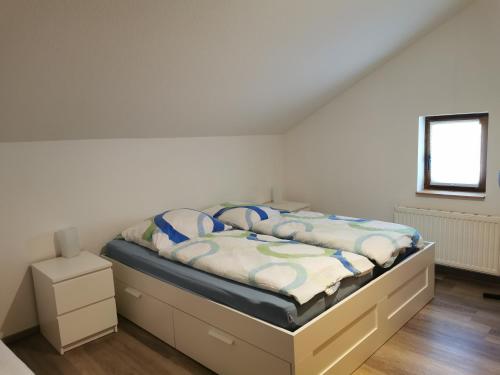 Cama en habitación con pared blanca en Beekenhof Ferienwohnung für Monteure, en Bommelsen