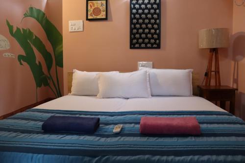 a bed with three pillows on it in a room at Da Mantra House in Tiruvannāmalai