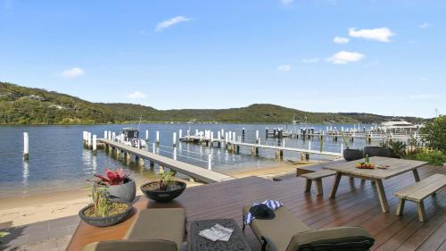 a dock with a table and chairs next to the water at Riptides Booker Bay -Waterfront apartment, walk to shops & cafes in Booker Bay