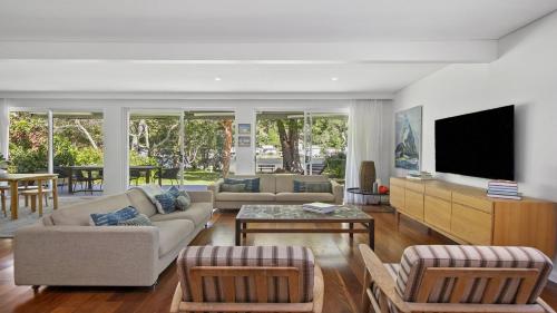 a living room with couches and a flat screen tv at The Patonga Pearl in Patonga