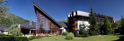 a large building on a hill with a green yard at Mercure Saint-Lary in Saint-Lary-Soulan