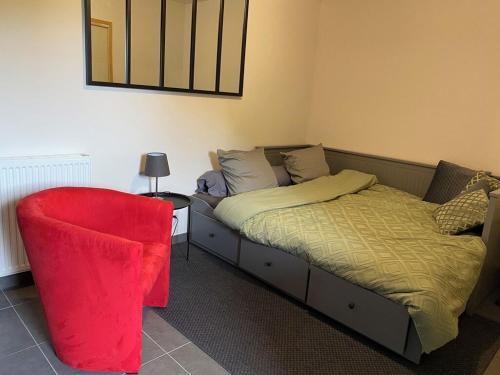une chambre avec un lit et une chaise rouge dans l'établissement TAMA, à Saint-Lunaire