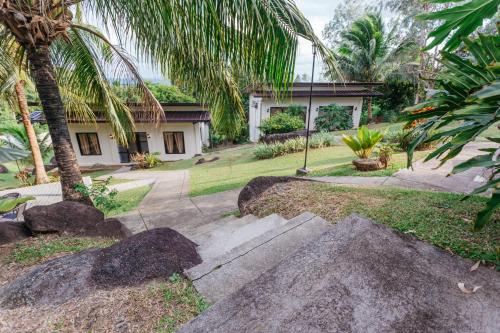 a house with a palm tree and a sidewalk at Spacio Caliraya Bed & Breakfast in Lumban