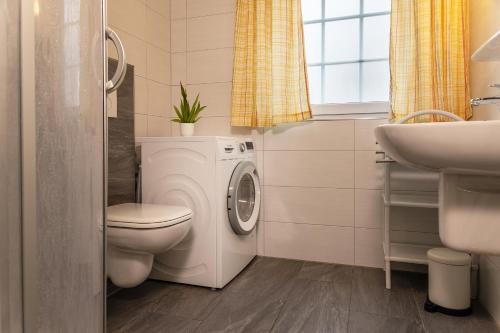 een badkamer met een wasmachine, een toilet en een wastafel bij 50038... in Carolinensiel
