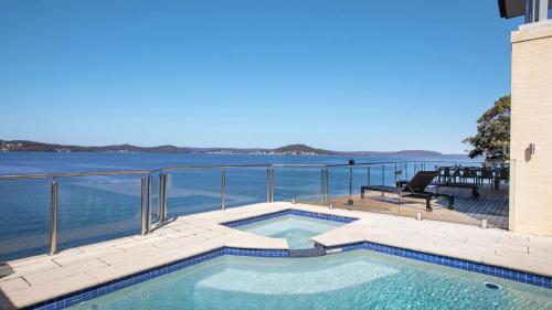 a swimming pool with a view of the water at Waters Edge - Point Clare - Pool - Spa - Private Jetty in Point Clare