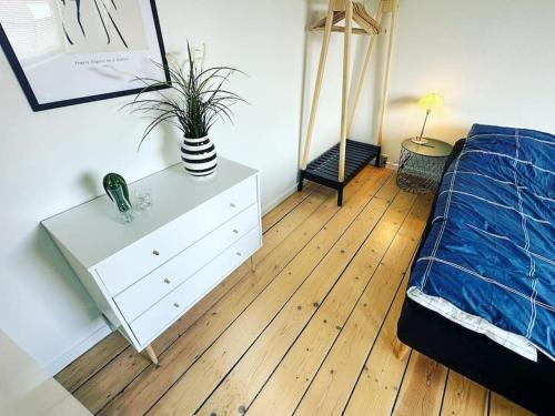 a bedroom with a bed and a dresser with a plant on it at Modern apartment for 6 in city center in Aalborg