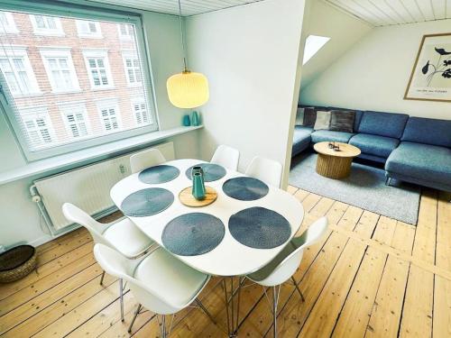 a dining room table with white chairs and a couch at Modern apartment for 6 in city center in Aalborg