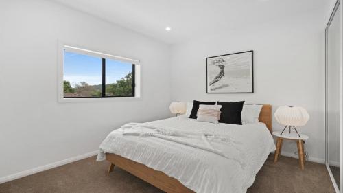 a white bedroom with a bed and a window at Bay Bliss U1 - Booker Bay in Booker Bay