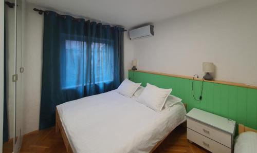 a bedroom with a white bed and a blue curtain at Central Home Away From Home in Shkodër