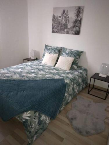 a bedroom with a bed with a blue blanket and pillows at Appartement Cosy avec Terrasse in Vaux-sur-Seine