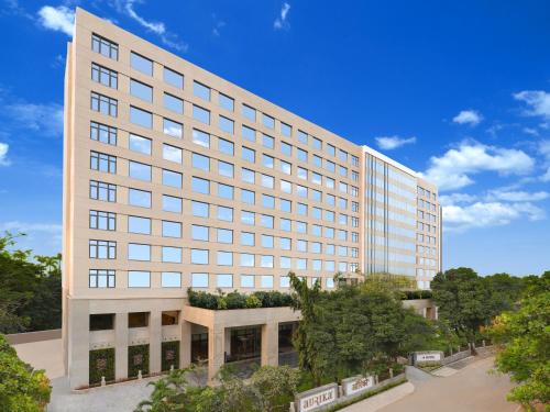 a large white building with trees in front of it at Aurika, Mumbai Skycity - Luxury by Lemon Tree Hotels in Mumbai