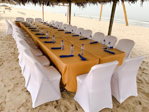 a long table on the beach with white chairs at Bojo Beach Resort in Bortianor