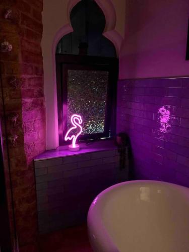 a bathroom with a bath tub and a neon sign in a window at Chapter Two - Melbourne in Melbourne