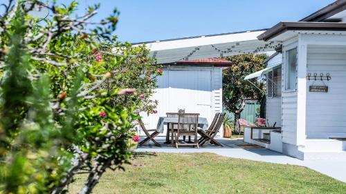 a patio with a table and chairs next to a house at Bangalow Beach House - Ettalong, pet friendly, walk to beach,shops,cafes in Ettalong