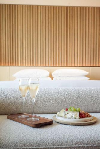 two glasses of wine and a plate of food on a bed at Park Hyatt Chicago in Chicago