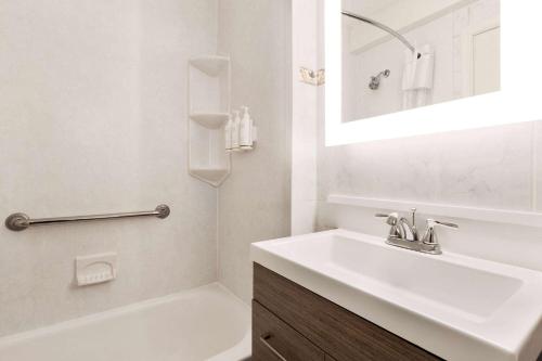 Baño blanco con lavabo y bañera en Days Inn by Wyndham Ocean City Oceanfront en Ocean City