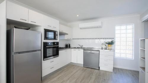 a kitchen with white cabinets and a stainless steel refrigerator at Beach Vibes at Terrigal in Terrigal